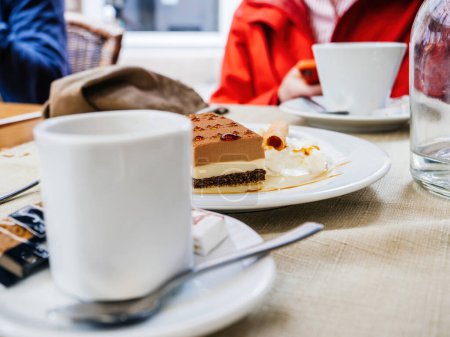 Téléchargez les photos : Une femme en rouge prend un repas à table avec un gâteau, du café et des ustensiles. - en image libre de droit