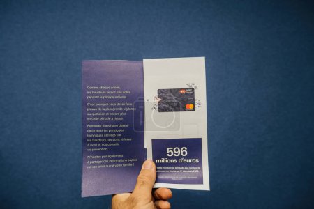 Foto de París, Francia - 12 de julio de 2023: Una persona que tiene un folleto abierto con comunicación para servicios bancarios. El folleto muestra el fraude de HSBCs en números de Francia - Imagen libre de derechos