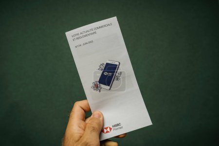 Foto de París, Francia - 12 de julio de 2023: Una persona que tiene un folleto para la comunicación bancaria con el logotipo de HSBC. - Imagen libre de derechos