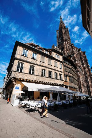 Téléchargez les photos : Strasbourg, France - 7 juil.2023 : La cathédrale Notre-Dame de Strasbourg, ville à l'architecture charmante et à l'histoire riche, domine le paysage urbain. Un point de repère à couper le souffle à côté de Maison Kammerzell - en image libre de droit