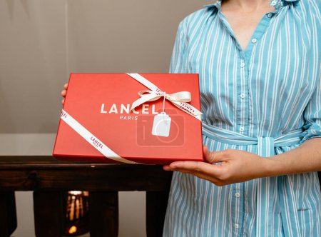 Photo for Paris, France - Aug 25, 2023: A female salesperson elegantly presents a luxurious Lancel gift box in the store, unveiling a fashionable item contained within. The package is adorned with a tasteful - Royalty Free Image