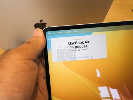 Téléchargez les photos : Strasbourg, France - 10 juil. 2023 : Dans le cadre distingué de l'Apple Store, une main masculine maintient une prise ferme sur le nouveau MacBook Air de 15 pouces, en inspectant minutieusement le prix, qui - en image libre de droit