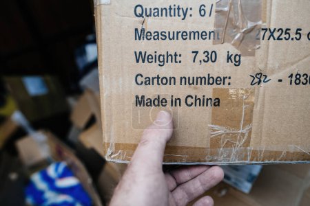Téléchargez les photos : Un doigt masculin pointe distinctement l'étiquette Made in China sur une boîte en carton, soulignant son lieu de fabrication - en image libre de droit