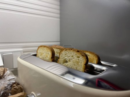 Foto de Cuatro rebanadas de pan cuidadosamente dispuestas en una tostadora, capturadas desde una vista lateral. - Imagen libre de derechos