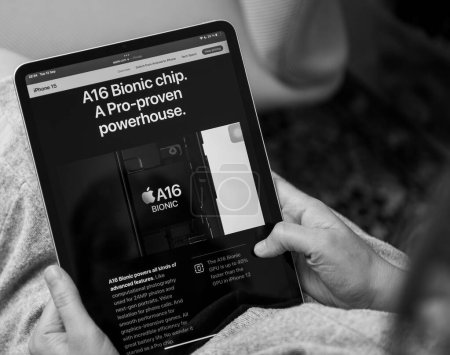 Foto de Londres, Reino Unido - 13 de septiembre de 2023: Leyendo el último anuncio de Apple, una mujer aprende sobre el chip A16 Bionic en el nuevo teléfono inteligente iPhone 15 - Imagen libre de derechos
