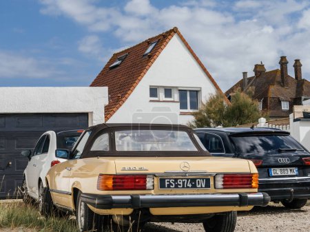 Photo for Neufchatel-Hardelot, France - Aug 18, 2023: A vintage Mercedes-Benz 380 SL elegantly parked in front of a house, flanked by an Audi wagon and a compact Fiat Mini car. - Royalty Free Image