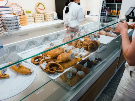 Téléchargez les photos : Une femme avec un détenteur d'argent ouvert achète des aliments sucrés traditionnels dans un café à l'aéroport de Palma de Majorque - en image libre de droit
