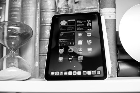 Foto de París, Francia - 25 de octubre de 2021: Un iPad Mini Pro descansa junto a un reloj de arena y una colección de libros de cuero vintage. - Imagen libre de derechos