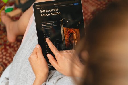 Téléchargez les photos : Londres, Royaume-Uni - 13 sept. 2023 : Une femme dans son salon parcourt le site Apple Computers sur son iPad Pro, découvrant le nouveau bouton d'action pour le dernier smartphone iPhone 15 Pro. - en image libre de droit