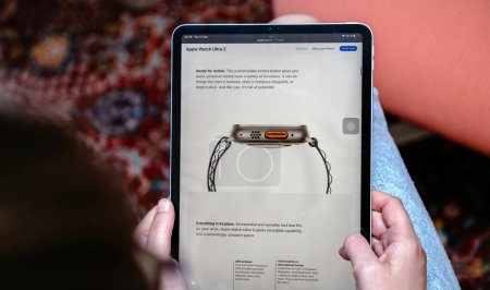 Foto de Londres, Reino Unido - 13 de septiembre de 2023: una mujer se adentra en el sitio web de Apple Computers en su tableta inteligente, detectando el llamativo botón de acción naranja que aparece en la pantalla del nuevo reloj inteligente Ultra 2 - Imagen libre de derechos