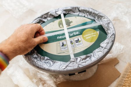 Photo for Frankfurt, Germany - Sep 13, 2023: Male POV: hand inspects safety strings on a large Indeko Plus pot by Caparol, containing CapaGreen paint, for secure mail transport. - Royalty Free Image