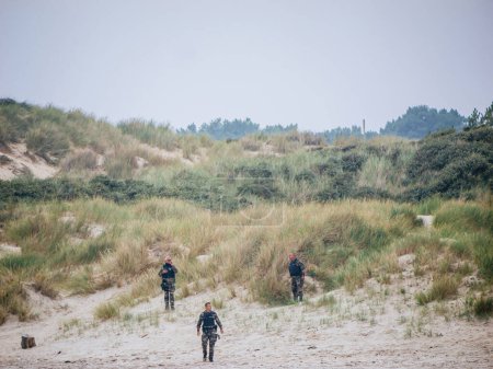 Photo for Neufchatel-Hardelot, France - Aug 18, 2023: French police officers and gendarmes conduct vigilant search and surveillance operations among the dunes, diligently working to apprehend illegal migrants - Royalty Free Image