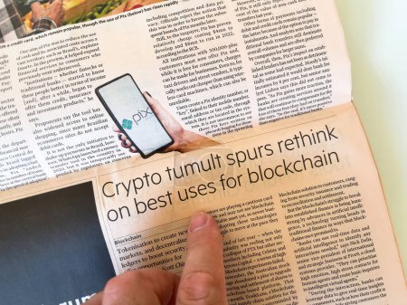 Foto de París, Francia - Sep 18, 2023: Hombre señala el artículo de FT "Crypto Tumult Spurs Rethink on Best Uses for Blockchain", destacando una reevaluación de la utilidad blockchain en medio de la volatilidad - Imagen libre de derechos