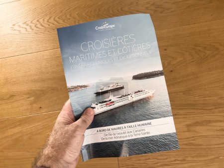 Photo for Paris, France - Sep 18, 2023: A mans hand holds a glossy brochure featuring cruises offered by Croisi Europe, a leading cruise operator. - Royalty Free Image