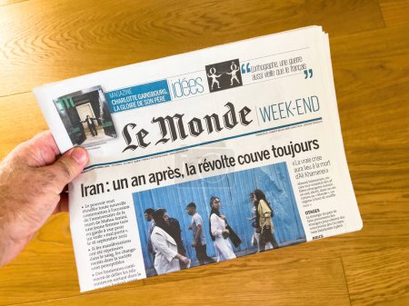 Téléchargez les photos : Paris, France - 18 sept. 2023 : un coup de main tient le journal "Le Monde" en évidence mettant en lumière les troubles en cours en Iran, un an après les premiers bouleversements - en image libre de droit