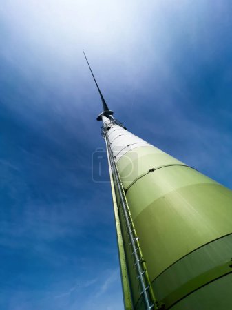 Foto de Una vista de baja perspectiva de un molino de viento contra un cielo azul, generando activamente electricidad a través de su fuente de energía renovable - Imagen libre de derechos