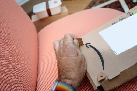 Foto de París, Francia - 5 de julio de 2023: Acercamiento de un hombre que desenvasa un paquete de Amazon Prime, capturando el momento de revelar el contenido de un paquete entregado recientemente - Imagen libre de derechos