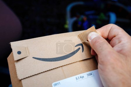 Photo for Paris, France - Jul 5, 2023: Using his fingers, a male hand delicately opens an Amazon Prime parcel, capturing the careful moment of unsealing a recently delivered package - Royalty Free Image