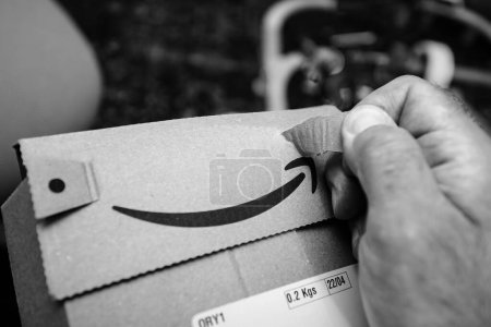 Photo for Paris, France - Jul 5, 2023: Close-up of a male hand using fingers to delicately open an Amazon Prime parcel, capturing the careful unsealing of a recently received package - Royalty Free Image