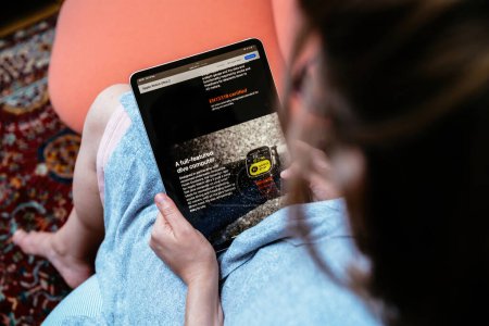 Téléchargez les photos : Londres, Royaume-Uni - 13 sept. 2023 :, une femme tient son iPad Pro, parcourant le site Web d'Apple Computers où elle apprend l'Apple Watch Ultra 2 riche en fonctionnalités, décrit comme un ordinateur de plongée complet - en image libre de droit