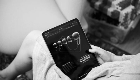 Téléchargez les photos : Londres, Royaume-Uni - 13 sept. 2023 : une femme est absorbée par son iPad Pro, en savoir plus sur le mode de transparence des ordinateurs Apple et les fonctionnalités de réduction du bruit pour les AirPods Pro 2e génération. - en image libre de droit