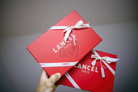 Photo for Paris, France - Aug 25, 2023: a male hand elegantly holding two red Lancel-branded cardboard gifts, emphasizing their premium quality. - Royalty Free Image