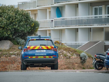 Téléchargez les photos : Neufchatel-Hardelot, France - 18 août 2023 : La vue arrière d'un VUS Skoda bleu, portant une inscription "Gendarmerie", est capturée garée près d'un immeuble d'habitation. - en image libre de droit