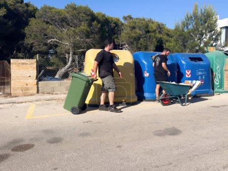 Photo for Mallorca, Spain - Jun 30, 2023: Workers are diligently removing construction waste into large plastic bins, situated on a street in Mallorca. - Royalty Free Image