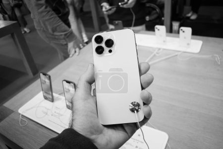 Foto de París, Francia - 19-sep-2023: Enfocado en el sistema de triple cámara, un hombre inspecciona la nueva Apple iPhone 15 Pro, terminada en titanio blanco. - Imagen libre de derechos