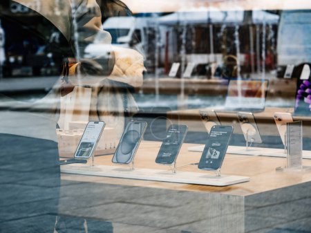 Téléchargez les photos : Paris, France - 22 sept. 2023 : Capturées à partir d'un point de vue extérieur, des silhouettes d'individus traversent les environs d'un Apple Store, où les iPhone 15 Pro et Max sont bien en évidence sur - en image libre de droit