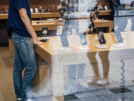 Téléchargez les photos : Paris, France - 22 sept. 2023 : Capturé en silhouette, un employé d'Apple Store consulte un client, guidant sa décision sur l'iPhone 15 Pro Max à acheter lors de son lancement. - en image libre de droit
