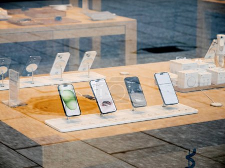Foto de París, Francia - 22-sep-2023: Desde la calle, una fila de presentaciones elegantemente arreglada de iPhone 15, 15 Pro y 15 Max es visible en una mesa de madera, marcando el día oficial de lanzamiento - Imagen libre de derechos