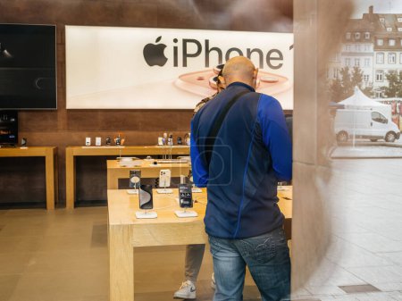 Foto de París, Francia - 22-sep-2023: El nuevo iPhone 15 Pro cautiva a un cliente dentro del Apple Store, que cuenta con un lujoso exterior de titanio - Imagen libre de derechos