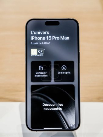 Photo for Paris, France - Sep 22, 2023: The new iPhone 15 Pro Max takes center stage on a wooden table, showcasing its demo wallpaper and a starting price of 1479 euros. - Royalty Free Image
