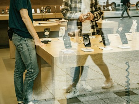 Téléchargez les photos : Paris, France - 22 sept. 2023 : Capturé en silhouette, un employé d'Apple Store consulte un client, guidant sa décision sur l'iPhone 15 Pro Max à acheter lors de son lancement. - en image libre de droit