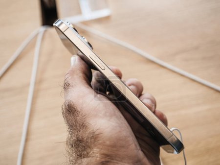 Téléchargez les photos : Paris, France - 22 sept. 2023 : Une main masculine tient le dernier iPhone 15 Pro en couleur titane blanc, en se concentrant sur le bouton d'alimentation, lors de son lancement mondial par Apple Computers. - en image libre de droit