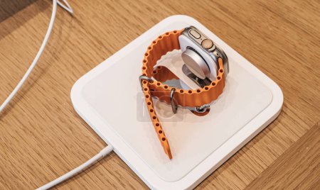 Photo for Paris, France - Sep 22, 2023: On a wooden table, the new Apple Watch Ultra 2 is plugged in and charging, signifying Apples continued advancement in wearable technology. - Royalty Free Image