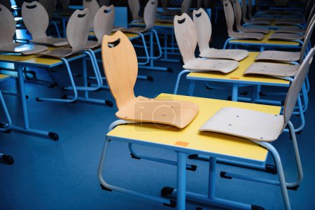 Foto de Después de las horas de limpieza, un comedor escolar impecable espera al día siguiente, sillas bien colocadas en las mesas como señal de limpieza - Imagen libre de derechos