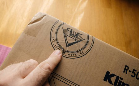 Photo for Munich, Germany - May 22, 2023: Male hand pointing at the iconic Klipsch Reference logo during the unboxing of high-end hi-fi speakers for a home cinema system - Royalty Free Image