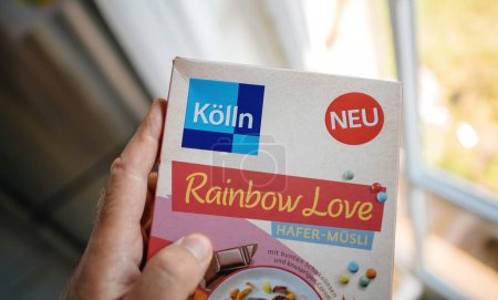 Foto de Frankfurt, Alemania - 12 de junio de 2023: En una cocina, un hombre sostiene un paquete de cereales Rainbow Love, producidos por Koln en Alemania. - Imagen libre de derechos