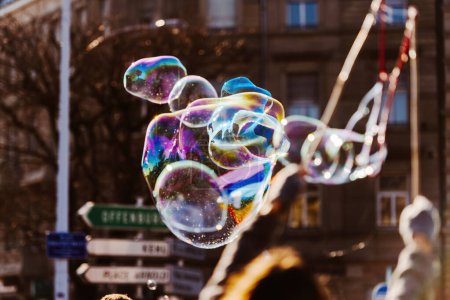 Foto de En el corazón de una bulliciosa plaza central, un artista experto cautiva a los espectadores creando burbujas de jabón de gran tamaño durante una animada reunión pública - Imagen libre de derechos