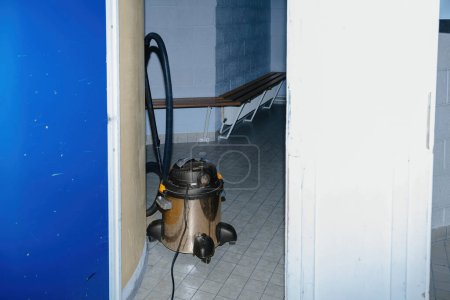 Foto de Aspiradora de grado industrial dejada desatendida en un gran pasillo dentro de una instalación educativa. - Imagen libre de derechos