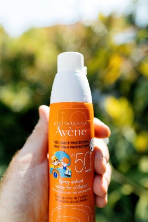Photo for Paris. France - Jun 3. 2023: In a POV shot on a sunny day, a male hand holds up the Eau Thermale Avene SPF50 spray for children with sensitive skin, emphasizing the importance of sun protection. - Royalty Free Image