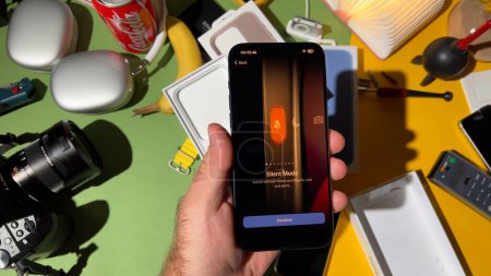 Téléchargez les photos : Londres, Royaume-Uni - 25 sept. 2023 : Gros plan d'une main masculine interagissant avec le bouton Action Mode silencieux sur le nouvel iPhone 15 Pro en titane dans une pièce conçue de manière créative - en image libre de droit