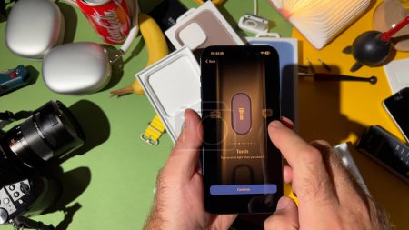 Téléchargez les photos : Londres, Royaume-Uni - 25 sept. 2023 : Gros plan d'une main masculine interagissant avec le bouton Action avec des réglages de torche sur le nouvel iPhone 15 Pro en titane dans une pièce conçue de manière créative - en image libre de droit