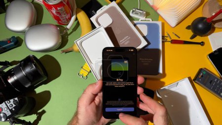 Téléchargez les photos : Londres, Royaume-Uni - 25 sept. 2023 : Gros plan sur un réglage manuel masculin Paiement Apple Pay sur le nouvel iPhone 15 Pro en titane dans une pièce conçue de manière créative - en image libre de droit