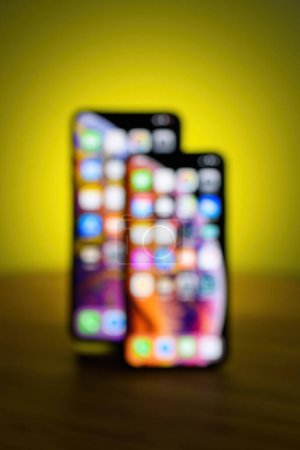 Photo for A defocused tableau of Big and Small smartphones on a tabletop, set against a vibrant and blurred backdrop - Royalty Free Image