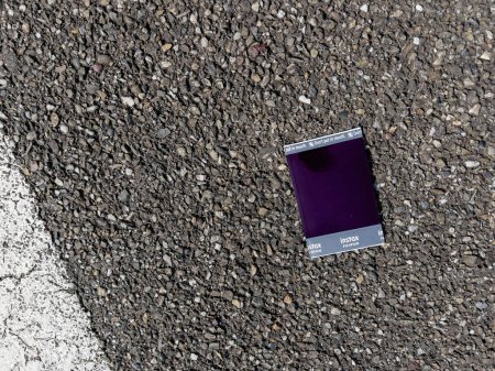 Foto de Estrasburgo, Francia - 30 de julio de 2022: Fujifilm Instax película instantánea descartada en la carretera urbana de asfalto. - Imagen libre de derechos
