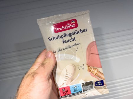Photo for Germany - Sep 25, 2023: A male hand grips a package of DM Profissimo shoe cleaning napkins, preparing to clean footwear. - Royalty Free Image