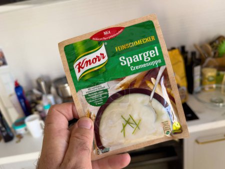 Foto de Londres, Reino Unido - 28 de septiembre de 2023: Una mano masculina sostiene un paquete de sopa instantánea Knorr Spargel Dry en una cocina moderna, mostrando una solución de comida fácil. - Imagen libre de derechos